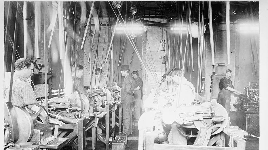 A factory floor around 1900, with a line shaft and belts running overhead